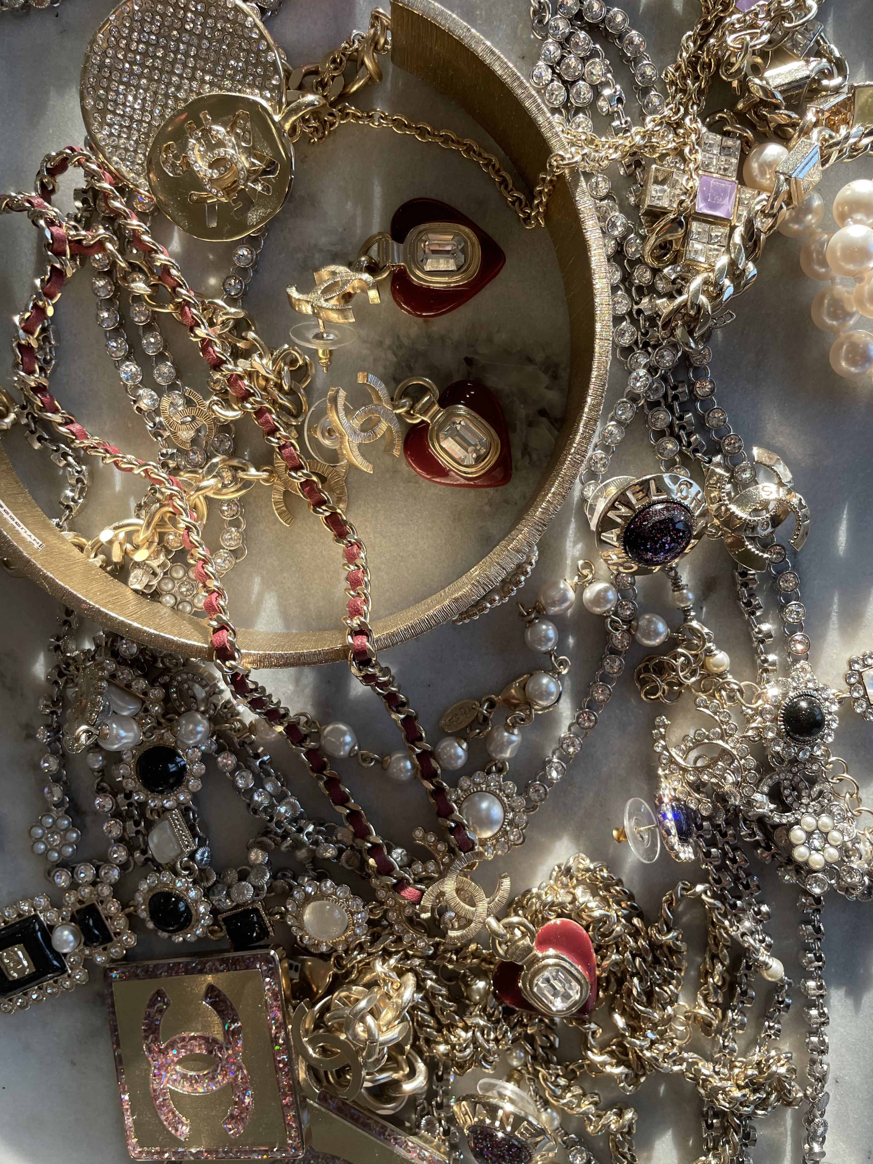 Chanel jewelry in and around a circular dish.