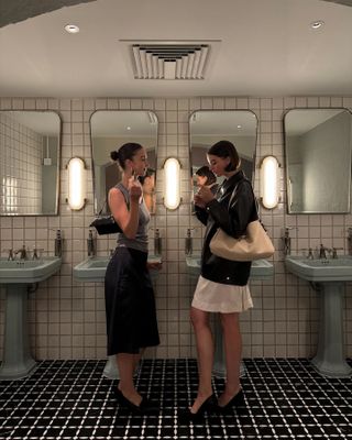 Two women reapplying makeup in the bathroom