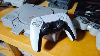 PS5 DualSense resting on right hand corner of original PS1 with 8Bitdo Retro Receiver inserted into port 1. 