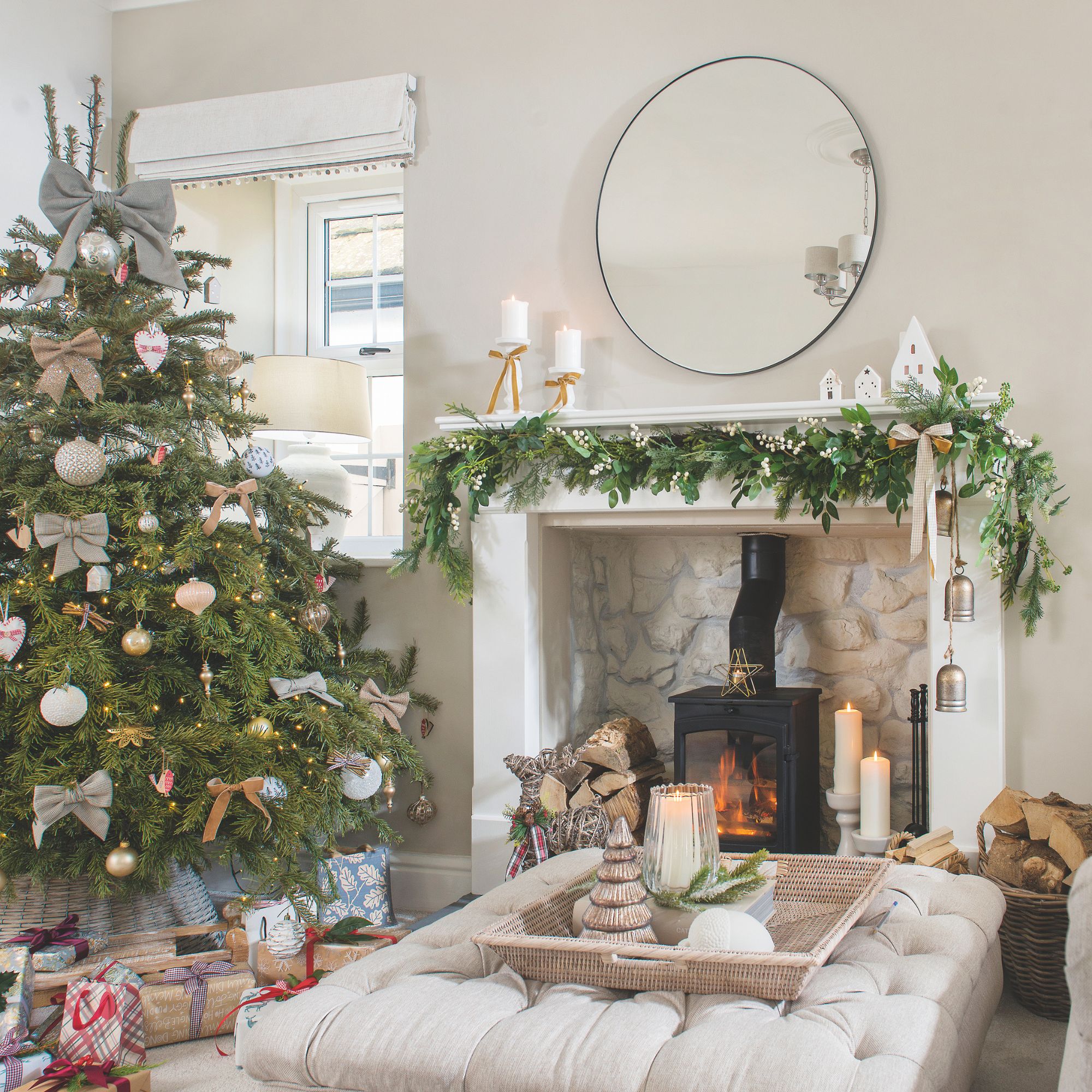 Festive living room with a log burner, footstool with accessory tray on it, and a christmas tree behind it