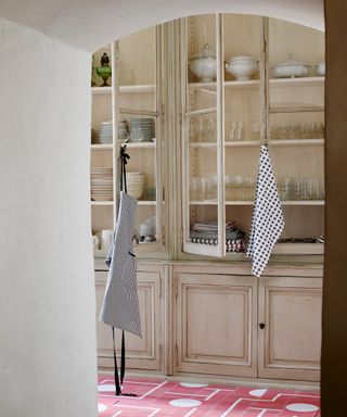 An example of kitchen shelving ideas showing a large glass fronted kitchen storage unit with wooden cabinets