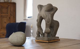 Stone object depicting two children and an adult, alongside a smooth, round stone and a glass candle holder