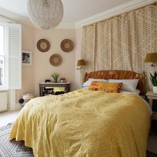 Bedroom with yellow bedspread and fabric wall hanging