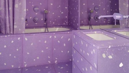 bright purple bathroom with matching wall and floor tiles, cabinet, taps and shower screen