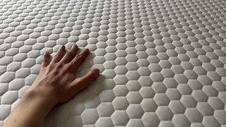 A hand feels the temperature of the Helix Premium Memory Foam Mattress Topper with GlacioTex.