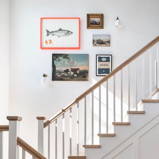 A white staircase with a small gallery wall with varied frames