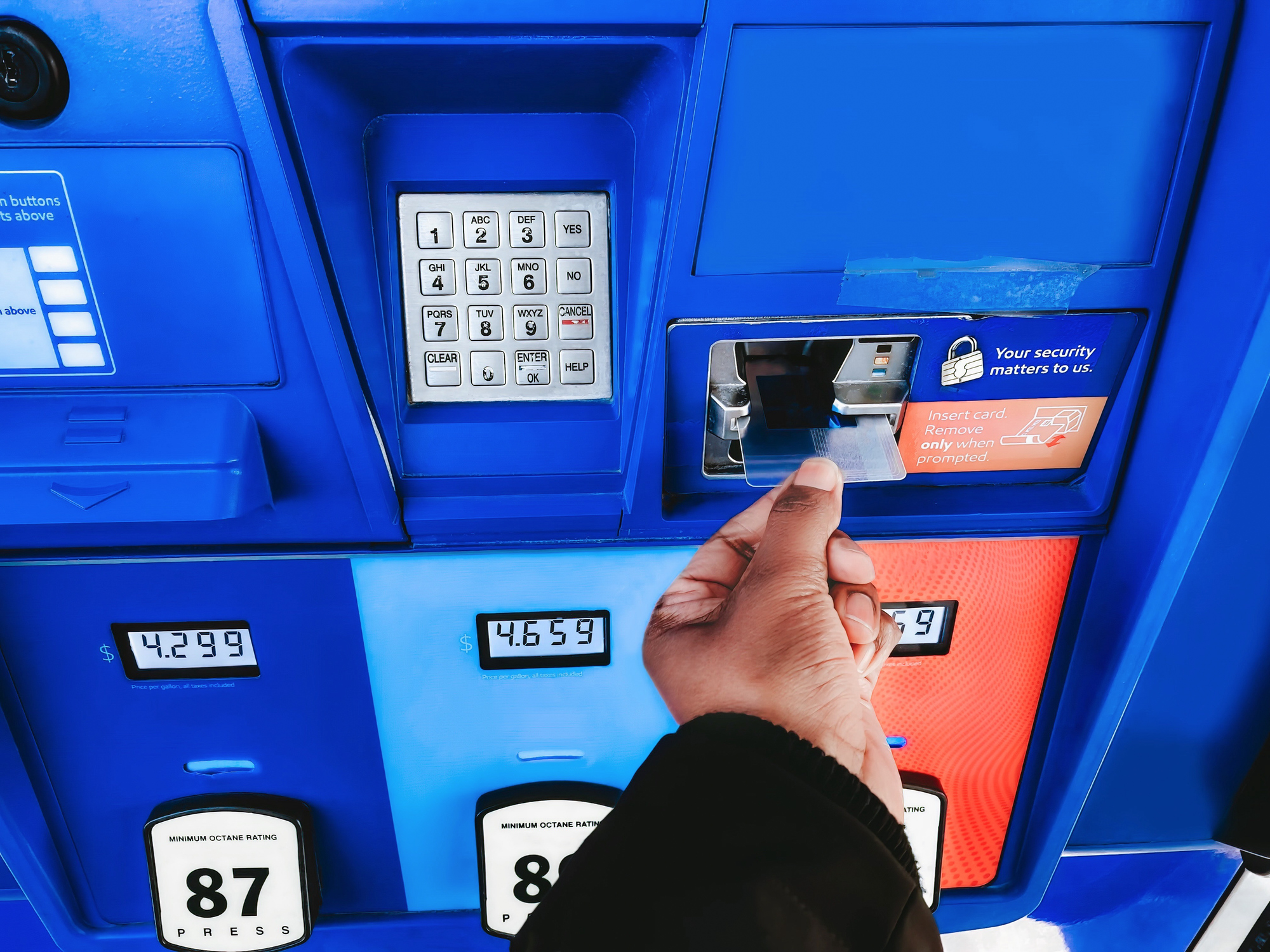 A woman inserts her credit card at a gas station pump.