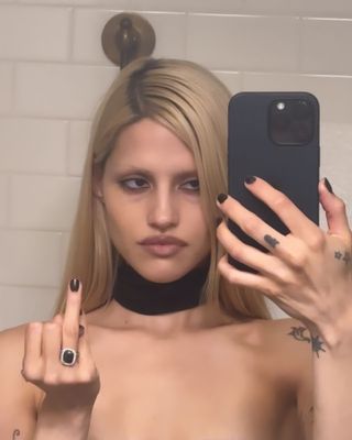 Gabbriette taking mirror selfie and wearing black diamond engagement ring.