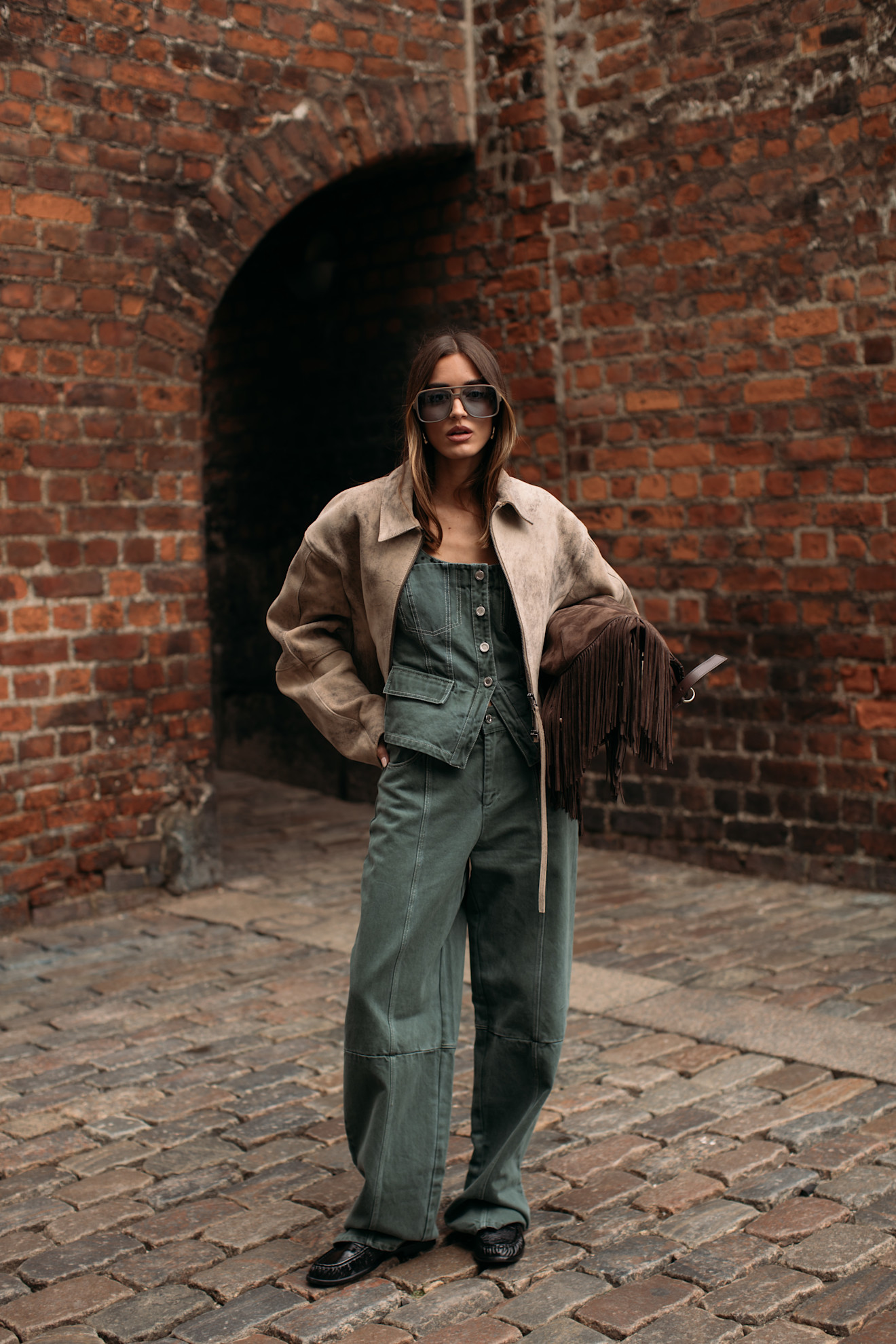 Woman wearing a suede jacket over a denim jumpsuit in Copenahgen