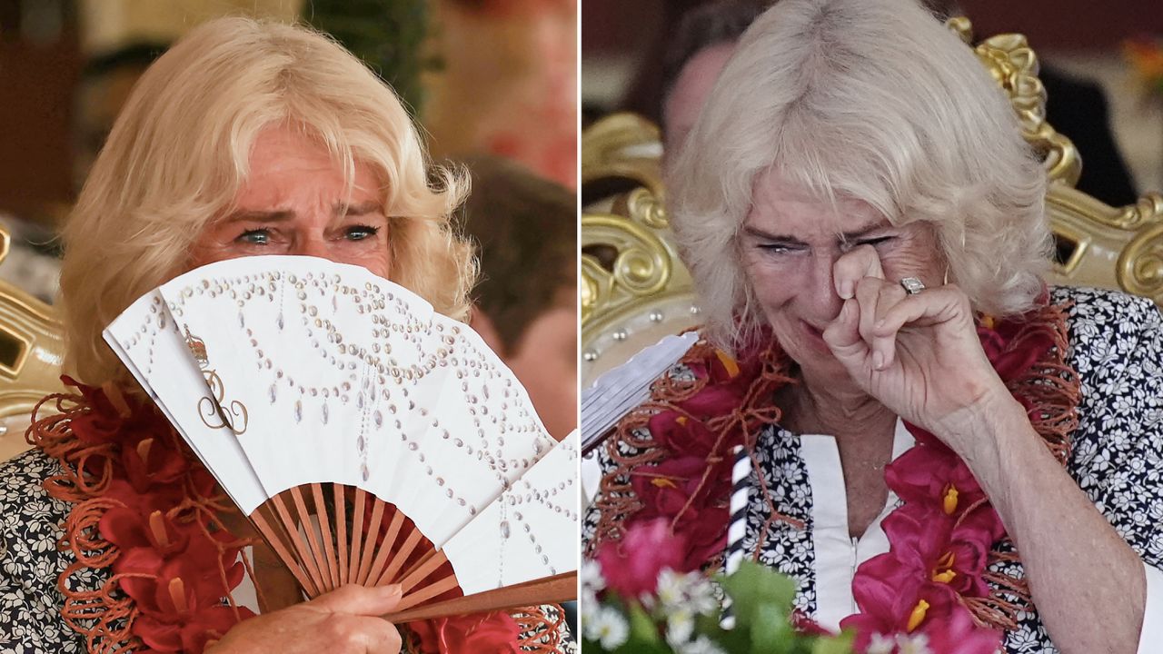 Queen Camilla crying behind a fan while wearing a floral dress during visit to Samoa on October 26, 2024