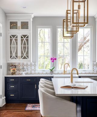 A dark blue and white kitchen with kitchen island, breakfast bar, and gold accents