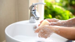 person washing their hands with soap and water in a sink