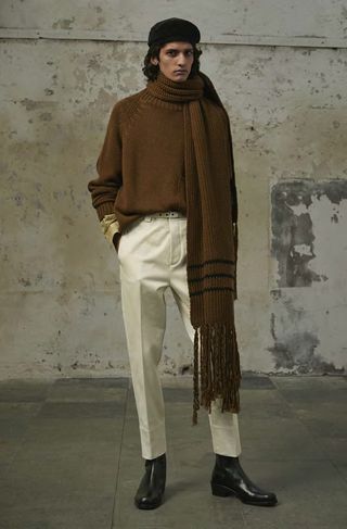 Man wears brown scarf with white trousers