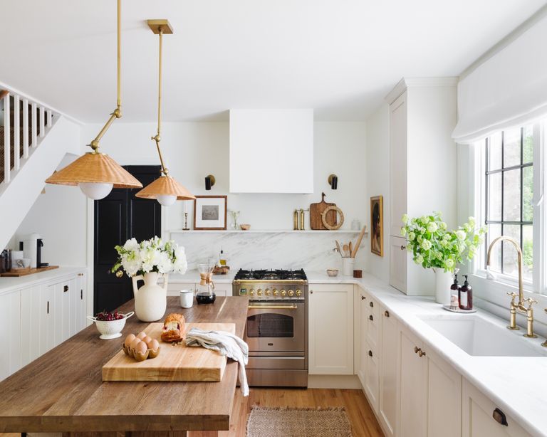 White kitchen with wooden island, wicker lampshades