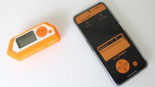 A Flipper Zero device next to a smartphone running the Flipper app