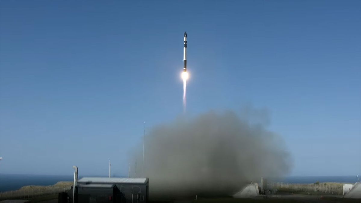 a white and black rocket climbs into a blue sky