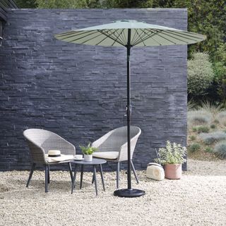 Bistro set and parasol in front of a slate garden wall