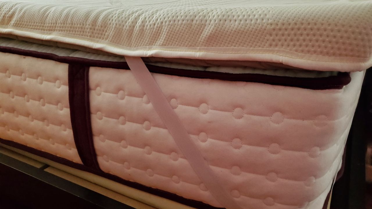 A close-up look at the Saatva Graphite Mattress Topper's anchor straps while placed upon a mattress.