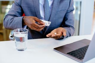 A man taking a pill from a blister pack.