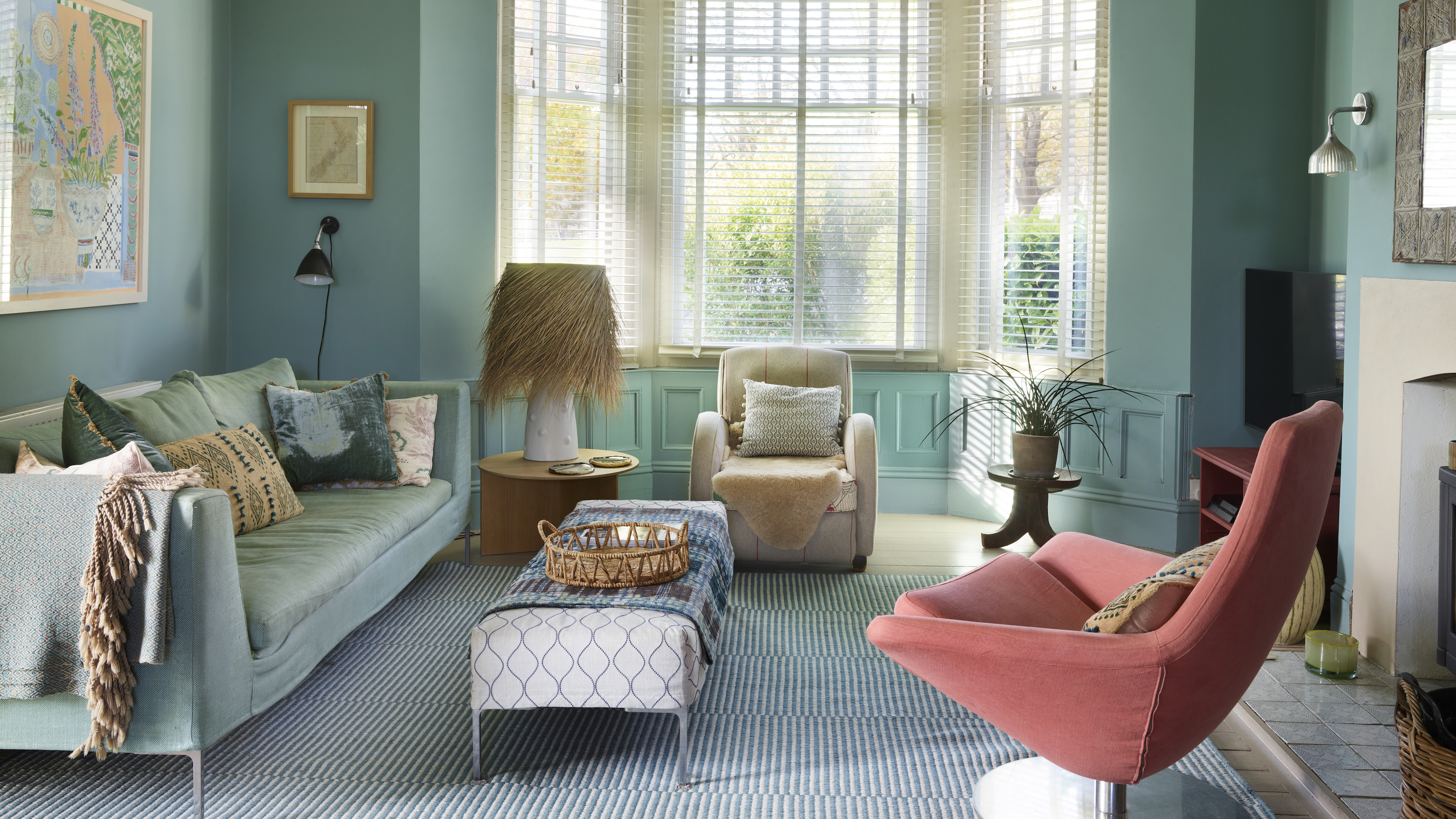 blue living room with pink armchair and a bay window