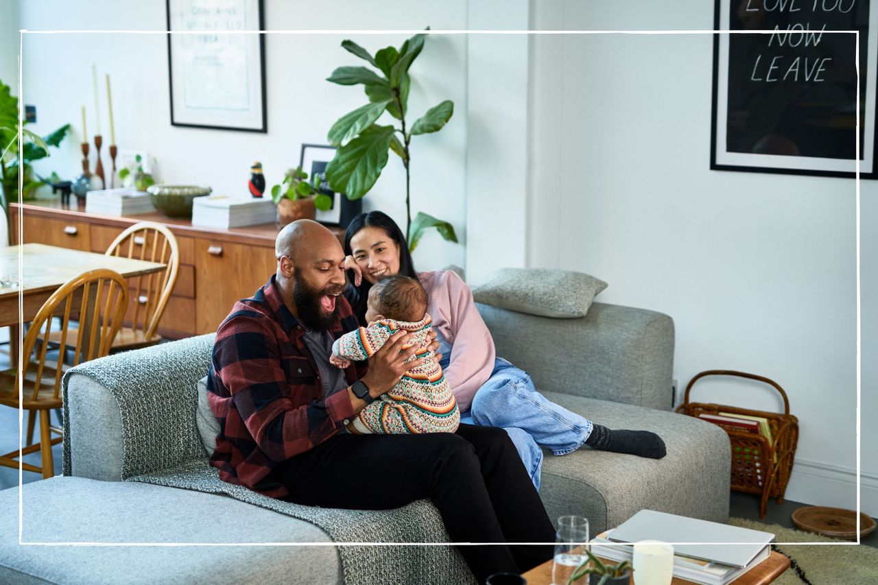 parents sitting on sofa at home playing with their baby