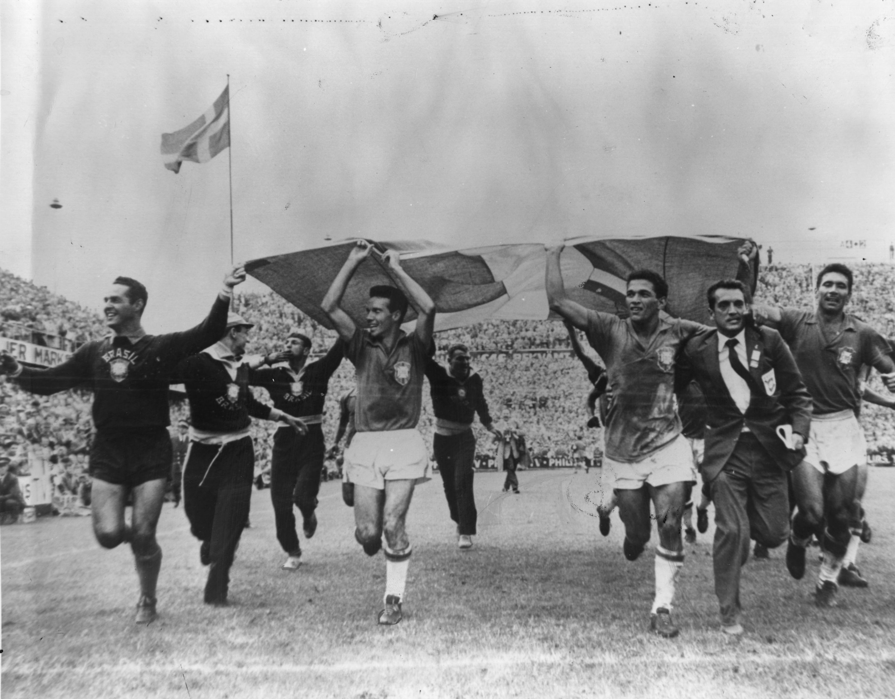 Brazil players run on the pitch with a Swedish flag after beating hosts Sweden in the 1958 World Cup final.