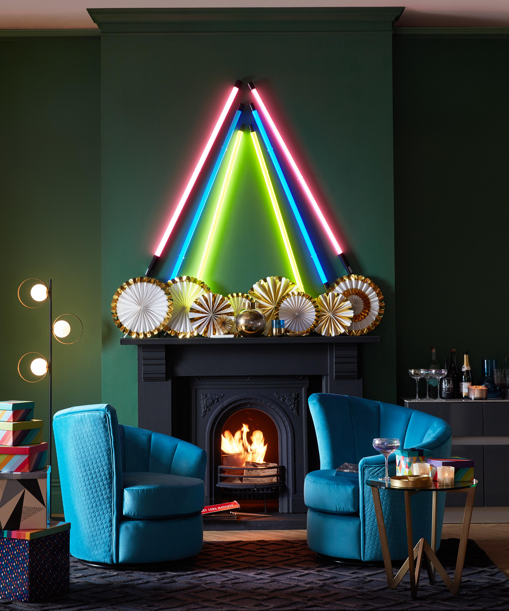 A modern living room with velvet blue sofas, foil fanned decoration and neon tube lights