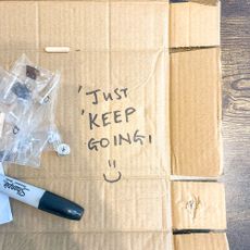 Flatted cardboard box with 'Just keep going' and a smiley face drawn on it
