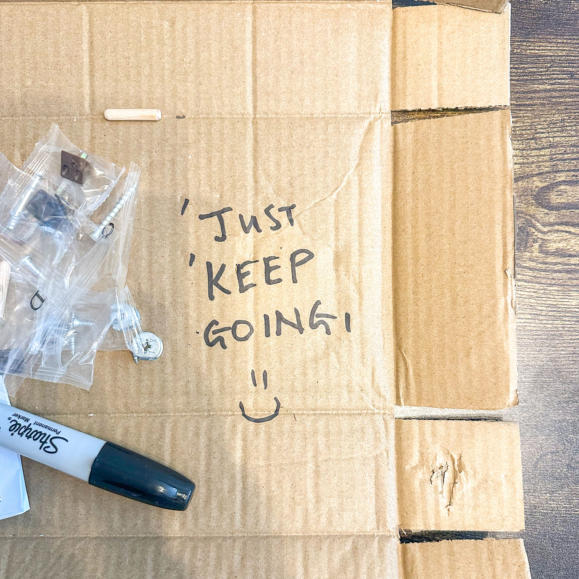 Flatted cardboard box with 'Just keep going' and a smiley face drawn on it