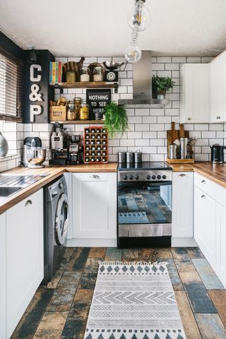 white industrial kitchen with coloured wooden floor, white metro tiles and open shelving