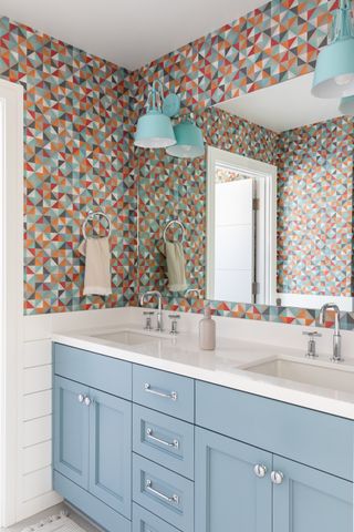 Bathroom with geometric wallpaper and blue vanity unit