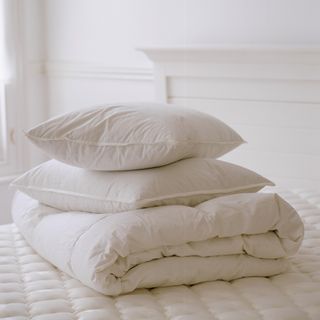 Folded white bedding on a white bed