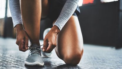 How long do running shoes last: woman lacing up trainers