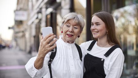 A grandmother and granddaughter take a selfie while out shopping together.