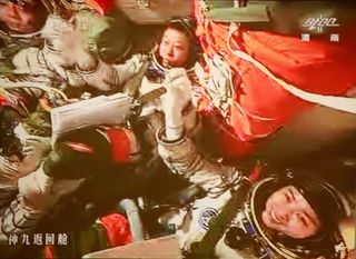 The three astronauts aboard China's Shenzhou 9 spacecraft grasp hands to celebrate their successful manned docking with the Tiangong 1 orbiting module on June 24, 2012. At center is astronaut Liu Wang, who piloted the successful docking. Mission commander Jing Haipeng is at left with astronaut Liu Yang, China's first female astronaut, at right.