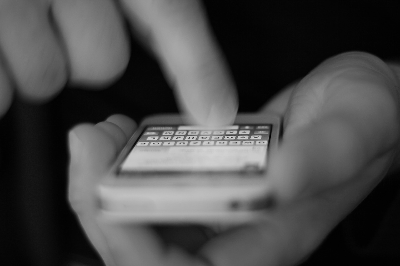 Are password managers safe - a monochrome image of someone typing on an iPhone