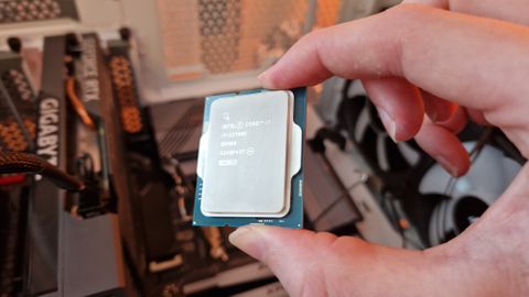 Intel Core i7-13700K being held by the reviewer above a gaming PC