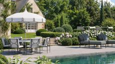 kathy kuo home outdoor poolside lookbook shot with striped pool loungers and a round table with patio umbrella and chairs