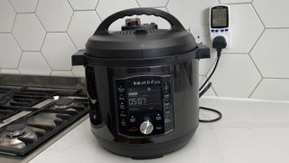 the Instant Pot Pro Crisp connected to an energy meter on a kitchen countertop