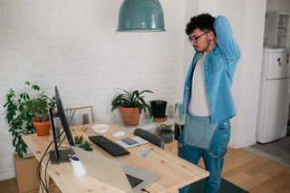 How to protect your eyes as a digital artist; a man stretches while stood over desk