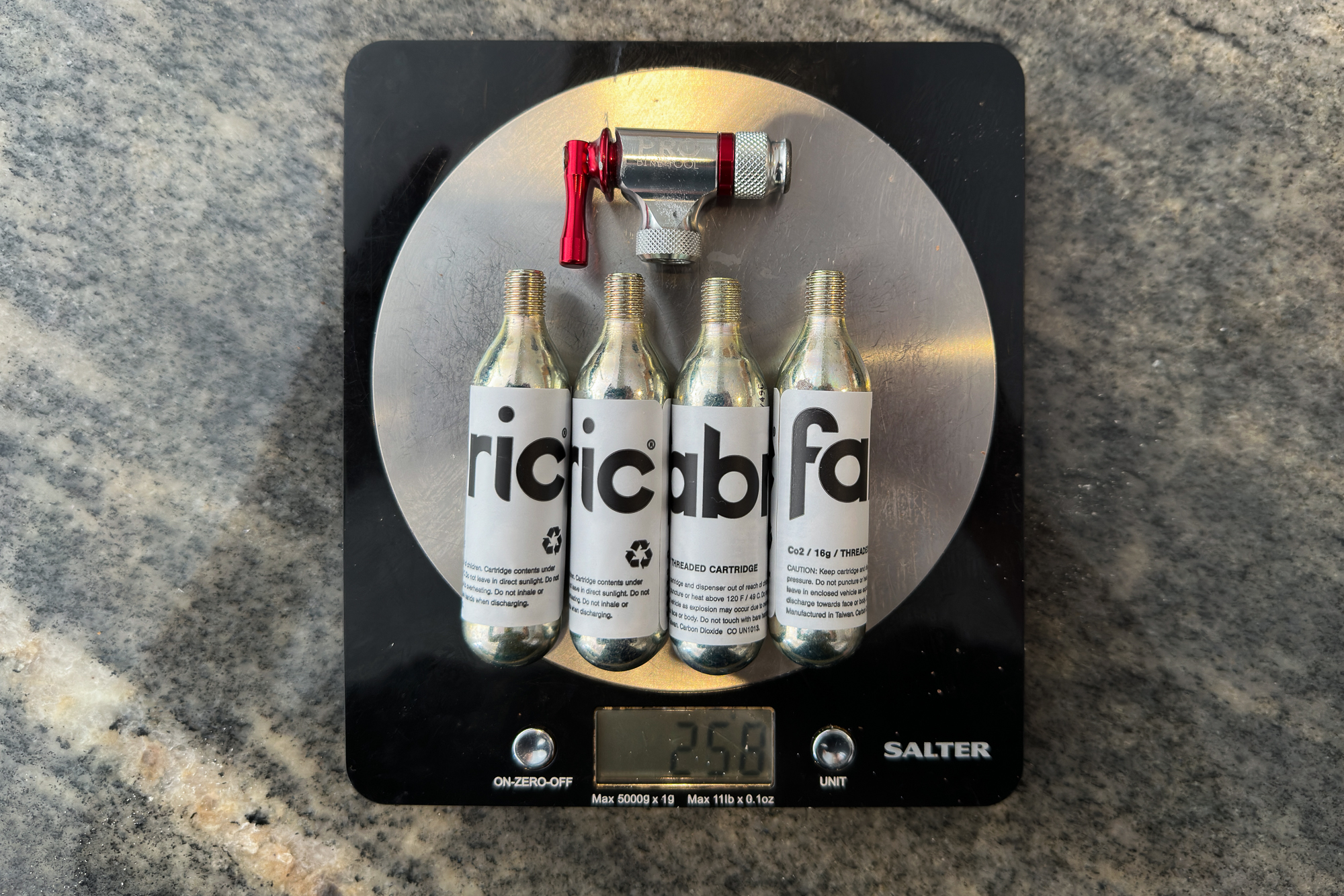 Image shows 4 CO2 canisters and an inflator on some digital scales, reading 250g