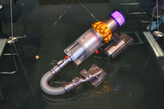 A photo of a Dyson stick vacuum with a pet grooming tool attachment