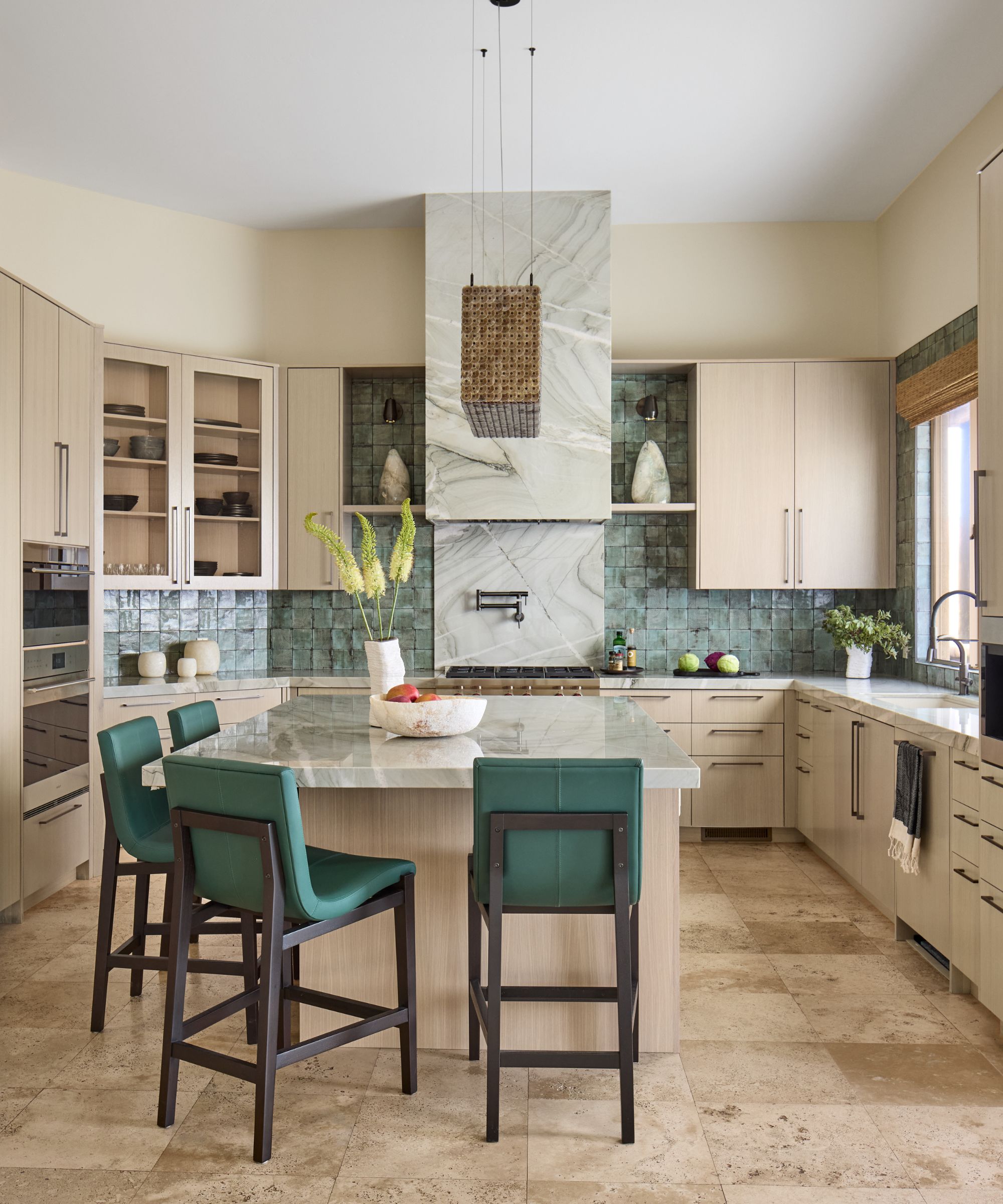 Light wood and stone kitchen, large island with blue seating, blue tiled backsplash.