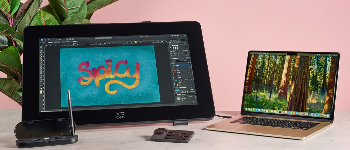 From left to right, there&#039;s a MacBook Air and XPPen drawing display with accessories. There&#039;s some brightly coloured artwork on the display that reads &quot;Spicy&quot;.