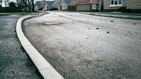 Surface level view of a newly tarmac pavement seen on a housing development of new bungalows