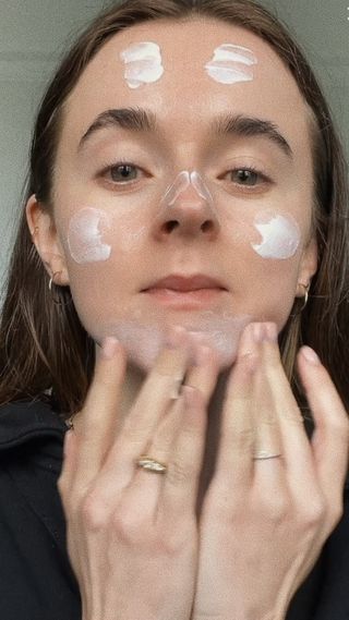 Esthetician, beauty writer and Who What Wear contributor Grace Day poses for a selfie while rubbing in affordable moisturiser into her skin.