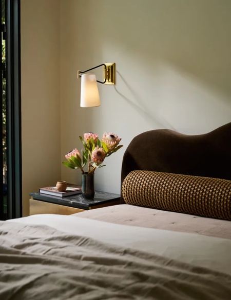 bedroom with scalloped headboard and gold wall light