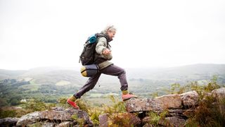 Woman walking across a wall in hiking gear and clothing