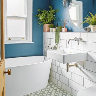bathroom with blue walls white tiles and oval bath