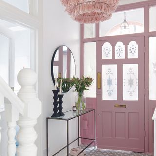 Hallway of a Victorian home with a pink front door and stained glass.